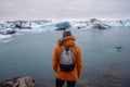 Man with a backpack standing on the beach against the background of an glacier lagoon with icebergs and views of the snow-capped