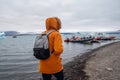 Man with a backpack standing on the beach against the background of an glacier lagoon with icebergs and views of the snow-capped