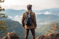 Man with backpack standing on the edge of a cliff and looking at the valley, Male tourist standing on top of a mountain and Royalty Free Stock Photo