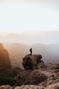 Man with a backpack standing on top of a cliff during the sunset Royalty Free Stock Photo
