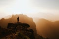 Man with a backpack standing on top of a cliff during the sunset Royalty Free Stock Photo