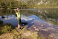 A man with a backpack stands with his hands raised. against the backdrop of a mountain lake with a beautiful reflection Royalty Free Stock Photo