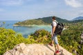 Man with backpack stands on mountain rock top and looks on beautiful seascape Royalty Free Stock Photo