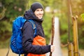 Man with backpack trekking in forest by hinged bridge over river. Cold weathe. Spring hiking. Wooden bridge across the river Royalty Free Stock Photo