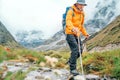 Man with backpack and trekking poles crossing mountain creek during Makalu Barun National Park trek in Nepal. Mountain hiking and