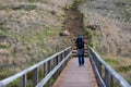 Man with a backpack waking over a boardwalk at a hiking trail