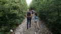 Man with backpack and woman hikers trekking in forest. Clip. Rear view of young couple walking with a group of travelers