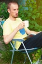 Man at backyard drinking coffee and reading book Royalty Free Stock Photo