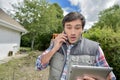 Man in backyard looking at tablet phone to ear shocked expression Royalty Free Stock Photo