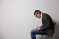 Man with bad posture using laptop while sitting on chair against grey background. Space for text Royalty Free Stock Photo