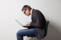 Man with bad posture using laptop while sitting on chair against grey background Royalty Free Stock Photo