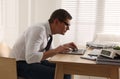 Man with bad posture working on laptop in office Royalty Free Stock Photo