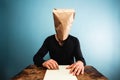 Man with bag over head writing letter