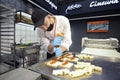 Man baker making sweet rolls putting tasty filling into dough. Mini bakery