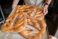 A man in a bakery takes traditional French Fougasse bread out of the oven.