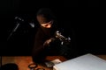 Man with balaclava holding gun. Sitting behind the desk poiting gun to the side Royalty Free Stock Photo