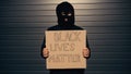 man in balaclava holding placard with