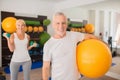 Man with a ball and a woman with dumbbells exercising together