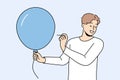 Man with balloon holds needle, wanting to make loud explosion to cheer people around