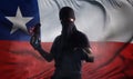 A man with a bandage on his face with a burning bottle in his hands on the background of the flag of Chile