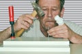 A man with a bandaged finger hammers a nail into the boards connected by a clamp Royalty Free Stock Photo