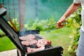 Man at barbecue grill preparing meat for a garden party Royalty Free Stock Photo