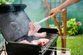 Man at a barbecue grill preparing meat for a garden party Royalty Free Stock Photo