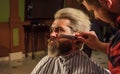 Man at barbershop. Hairdresser salon. Professional barber and client. Trimming beard close up. Maintaining beard shape Royalty Free Stock Photo