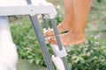 Man with bare feet using a ladder in a country swimming pool. Prevention of nail fungus and skin infections in the pool