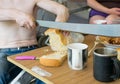 Man with a bare torso, sitting at the table, cuts a loaf of bread with a huge knife Royalty Free Stock Photo