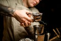 Man bartender holds steel squeezer and squeezes juice into shaker