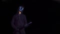 Man with a baseball bat in mysterious glowing mask. Anonymous swings on a black