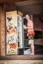 Man in bathing shorts takes cold beer from the fridge