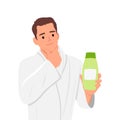 Man with bathrobe holding a hair product and thinking hand on chin. A man has a bottle of shampoo