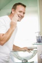 Man in bathroom applying shaving cream