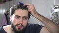 Man in the bathroom looking in a mirror and fixing his hair. Portrait of handsome man brushing his hair in bathroom Royalty Free Stock Photo