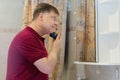 A man in the bathroom at mirror with an electric razor in his hands cleans