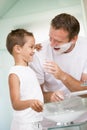 Man in bathroom putting shaving cream on young boy