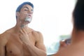 Man, bathroom and shaving beard in mirror with razor for hygiene and fresh skin with hair removal. Skin care, grooming Royalty Free Stock Photo