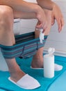 A man in the bathroom, sitting on the toilet, with his pants down, on the floor is a jar with wet wipes Royalty Free Stock Photo