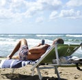 Man at the beach lying on the sunbed looking at the smartphone.