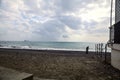 Man on a beach next to a building on a cloudy day