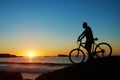 Man, beach and silhouette with mountain bike, sunset and mockup space by waves for summer cycling adventure. Cyclist