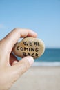 Man on the beach and text we are coming back Royalty Free Stock Photo