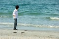 Man on beach throwing rocks into ocean