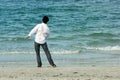 Man on beach throwing rocks into sea