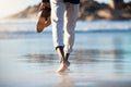 Man, beach and walking feet in water in summer with shoes in hand to relax, breathe and thinking. Ocean, walk and