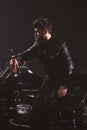 Man with beard, biker in leather jacket lean on motor bike in darkness, black background. Brutality and masculine