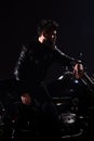 Man with beard, biker in leather jacket lean on motor bike in darkness, black background. Brutality and masculine