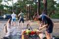 A man with a beard and black glasses sharpens a knife in nature while cooking. Outdoor recreation in summer. Bright and fresh